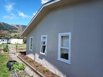 Same elevation in light grey stucco with three restored white windows