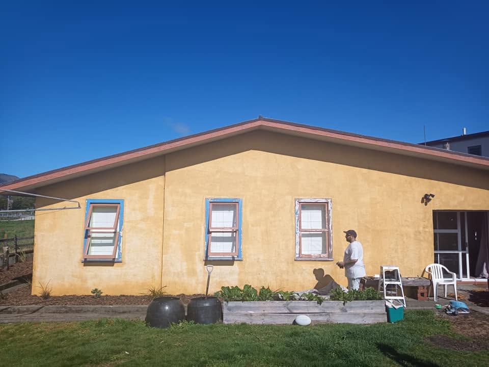 Yellow stucco wall with three weathered wooden windows before repair