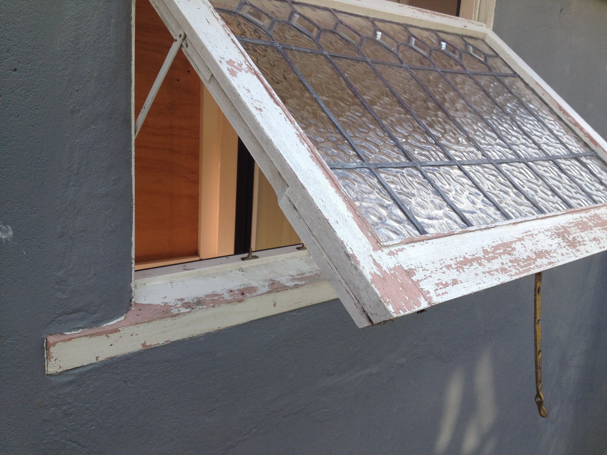 Weathered wooden leadlight window with peeling paint and failed putty