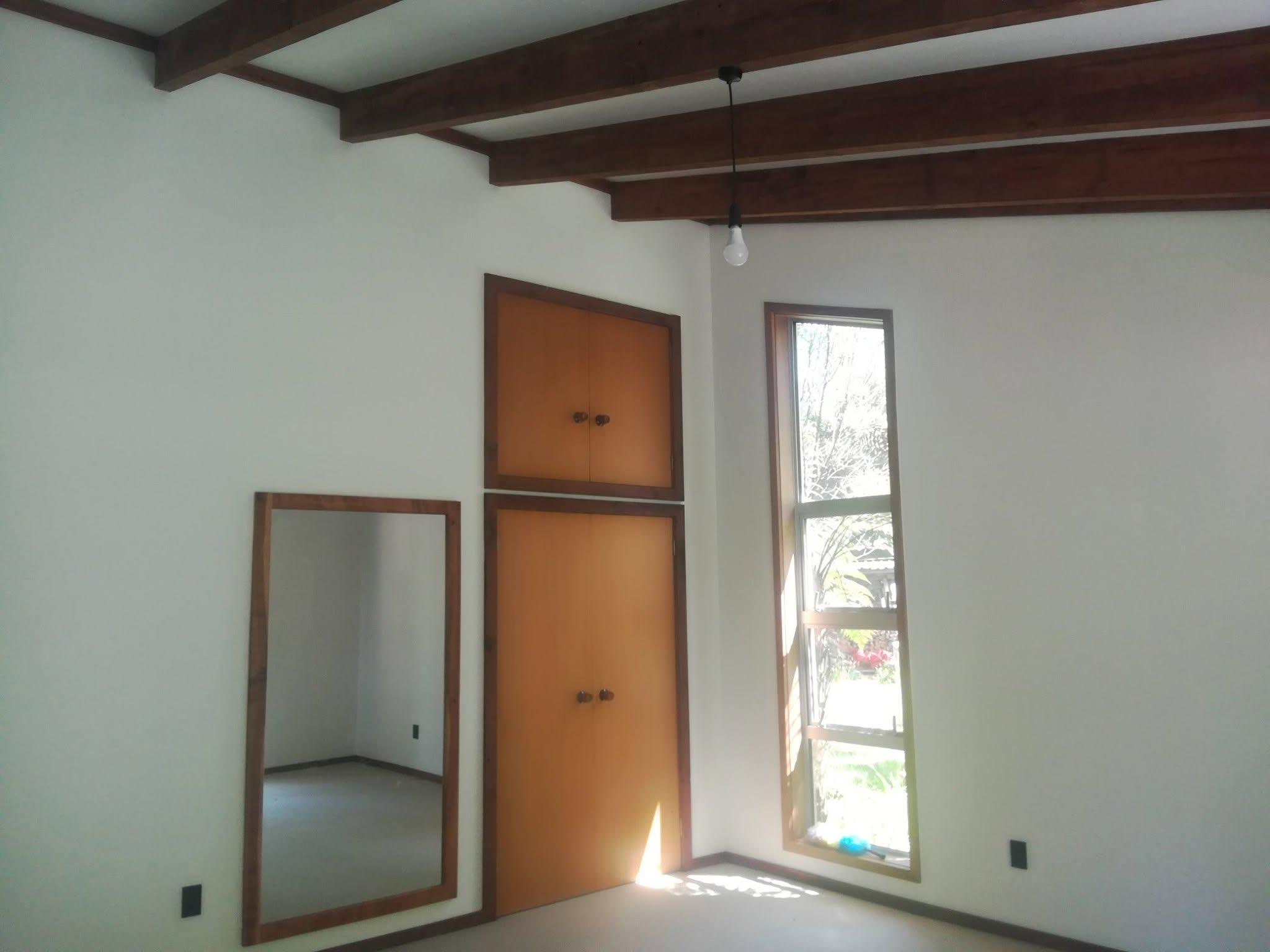 Same room finished in white with dark timber ceiling beams